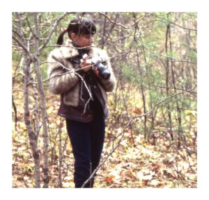 A young Paula Kennedy with camera in the woods